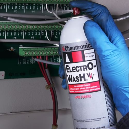 Gloved technician using Chemtronics Electro-Wash Tri-V contact cleaner on electrical components as a safer replacement for toxic solvents in degreasing and electronics cleaning.
